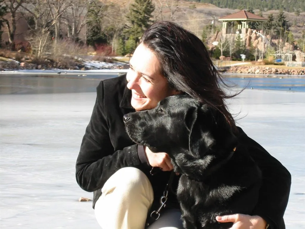 A woman sitting on the ground with her dog.