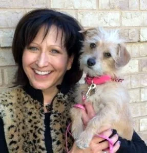 A woman holding a small dog in her arms.