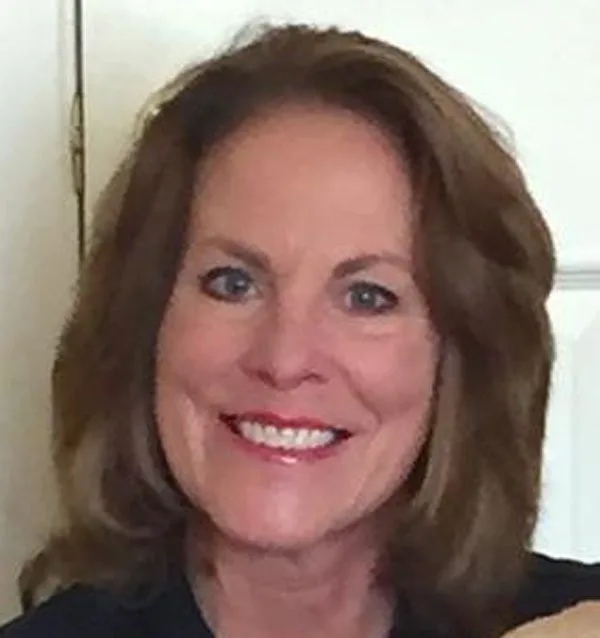 A woman with long hair and blue eyes smiling.